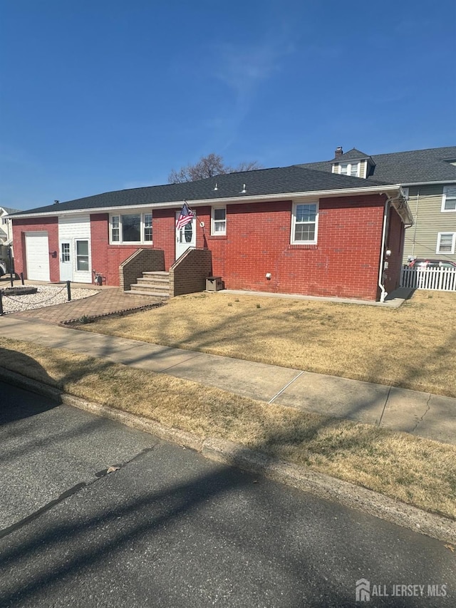 view of front of property featuring brick siding, entry steps, a front lawn, and fence