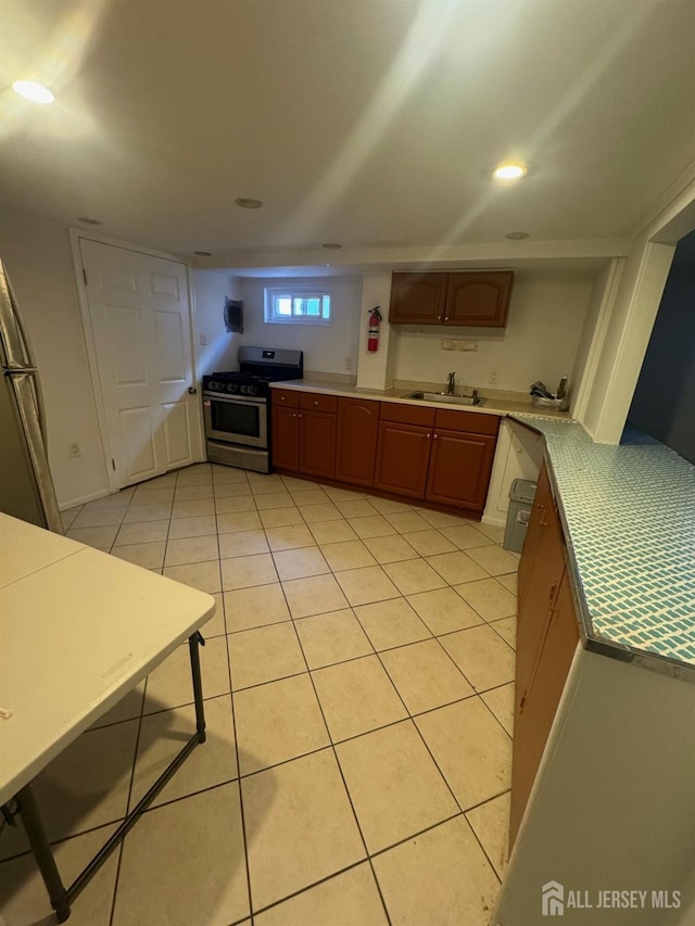 kitchen featuring a sink, gas stove, recessed lighting, light countertops, and light tile patterned floors