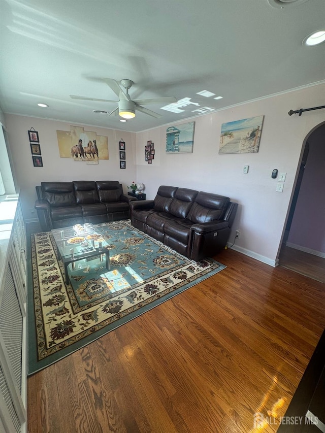 living room featuring wood finished floors, a ceiling fan, arched walkways, and baseboards