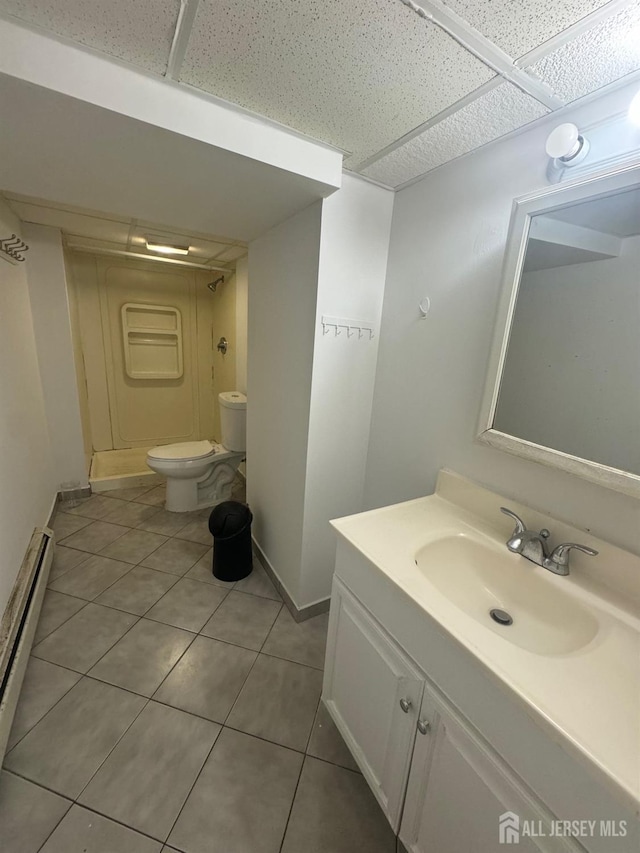 full bathroom with tile patterned floors, toilet, a drop ceiling, a shower stall, and baseboard heating