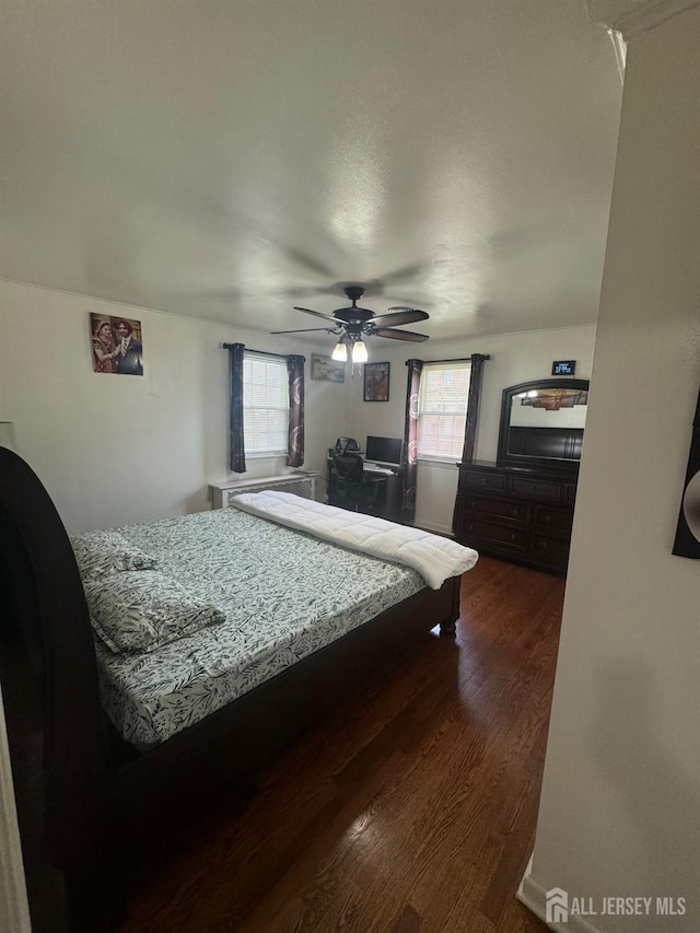 bedroom with a ceiling fan and dark wood-style flooring