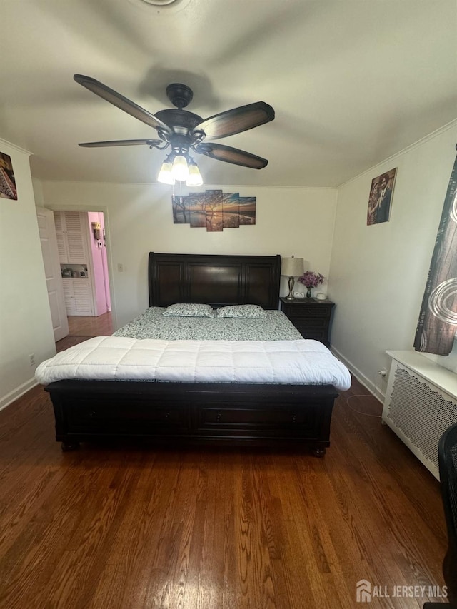 bedroom with baseboards, dark wood-type flooring, ceiling fan, and radiator heating unit