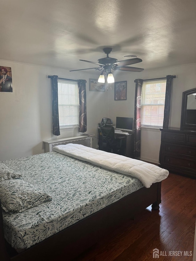 bedroom with multiple windows, dark wood-style floors, and ceiling fan