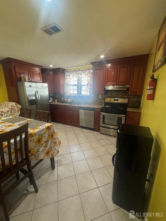 kitchen featuring visible vents, tasteful backsplash, stainless steel appliances, reddish brown cabinets, and light tile patterned floors