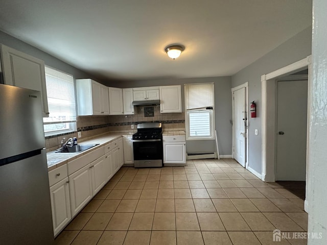 kitchen with range with gas cooktop, a baseboard heating unit, freestanding refrigerator, white cabinets, and a sink