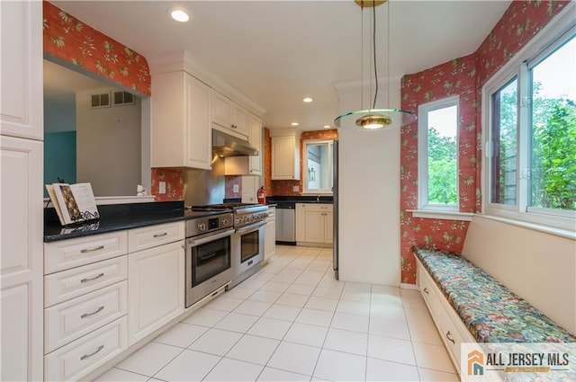130 Sayre Dr, Plainsboro, NJ 08540 - kitchen featuring appliances with stainless steel finishes, under cabinet range hood, dark countertops, decorative light fixtures, and wallpapered walls