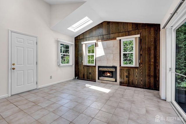 30 Daniel Dr, Matawan, NJ 07747 - unfurnished living room with lofted ceiling, wood walls, a skylight, plenty of natural light, and a tile fireplace