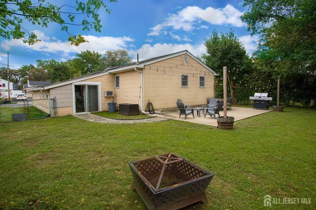 rear view of house featuring a wall mounted air conditioner, a yard, an outdoor fire pit, and a patio area