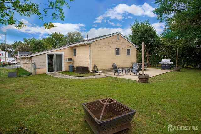 back of property with a fire pit, a patio, a lawn, and fence