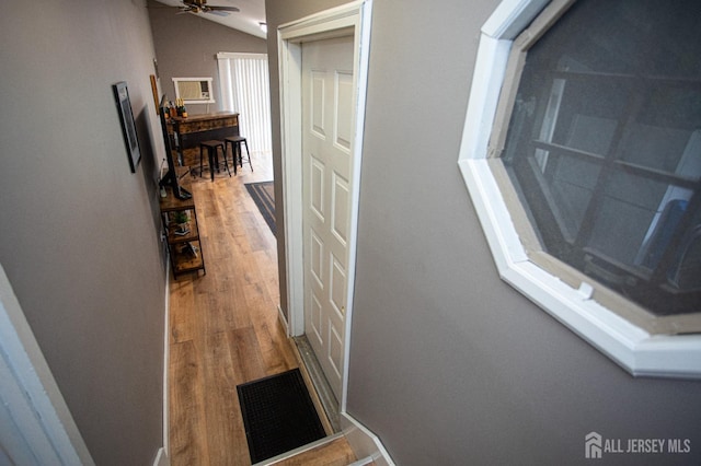 corridor with vaulted ceiling, wood finished floors, and visible vents