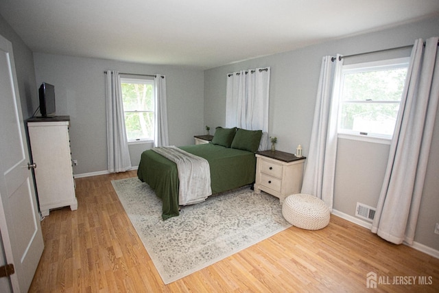 bedroom featuring baseboards, visible vents, and wood finished floors