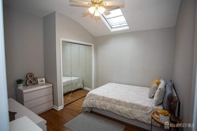 bedroom featuring vaulted ceiling with skylight, a closet, a ceiling fan, and wood finished floors