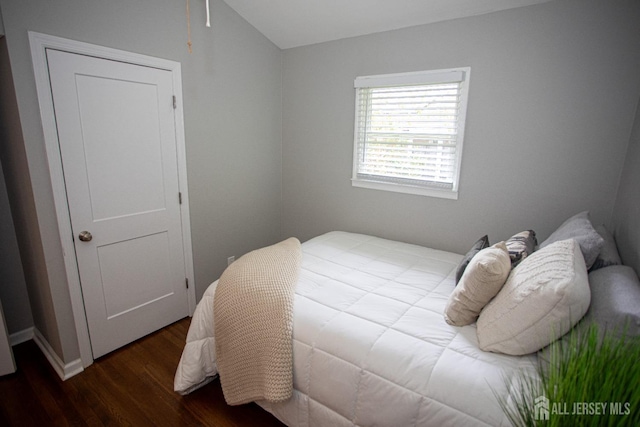 bedroom with lofted ceiling and dark wood-style floors