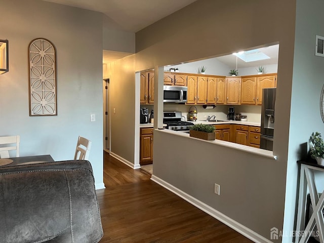 kitchen featuring dark wood finished floors, stainless steel appliances, light countertops, visible vents, and vaulted ceiling