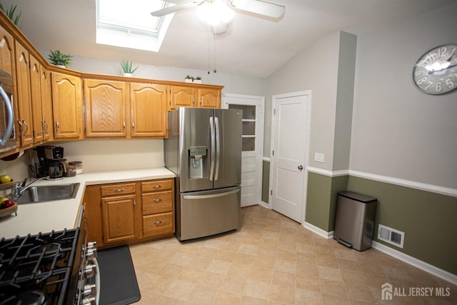 kitchen featuring stainless steel fridge with ice dispenser, lofted ceiling with skylight, ceiling fan, and sink