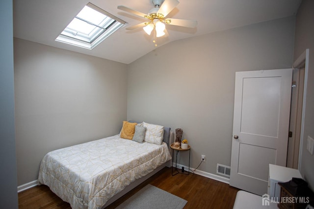 bedroom with ceiling fan, vaulted ceiling with skylight, dark wood-type flooring, and baseboards