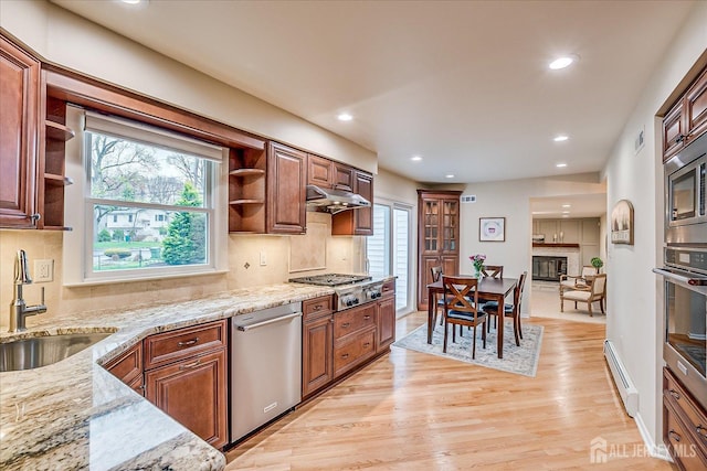 kitchen featuring open shelves, light wood finished floors, stainless steel appliances, and a sink