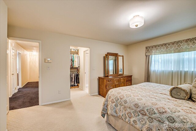 bedroom with baseboards, carpet flooring, a spacious closet, and a closet
