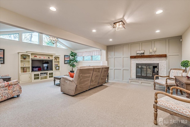 living area with recessed lighting, a glass covered fireplace, carpet, and lofted ceiling