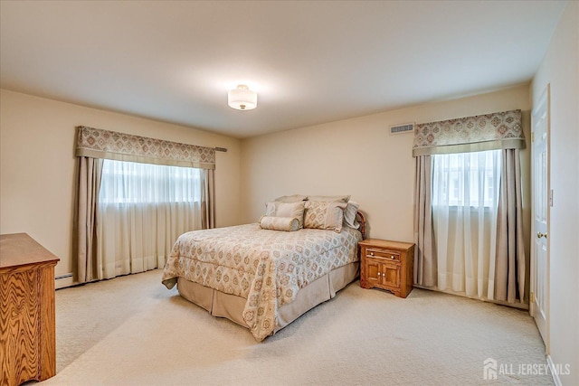 bedroom with baseboard heating, visible vents, light colored carpet, and multiple windows