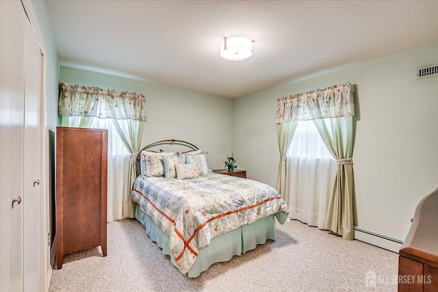 bedroom with a baseboard heating unit, light carpet, and visible vents
