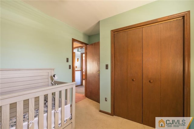 bedroom featuring light carpet, a crib, and a closet