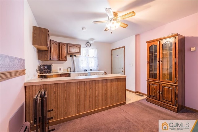 kitchen featuring kitchen peninsula, light carpet, baseboard heating, and ceiling fan