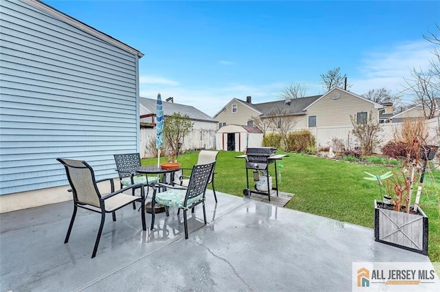 view of patio with a storage shed, an outbuilding, fence, grilling area, and outdoor dining space