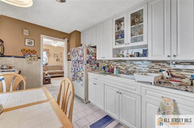 kitchen featuring light tile patterned floors, glass insert cabinets, light countertops, white cabinets, and freestanding refrigerator