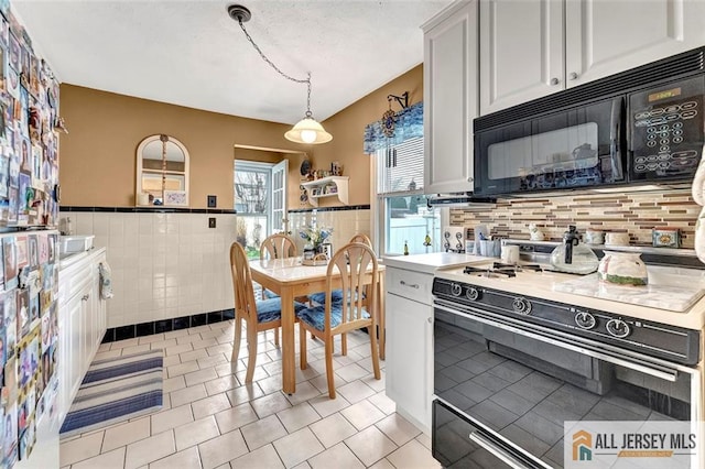 kitchen with range with gas stovetop, tile walls, light tile patterned floors, black microwave, and light countertops