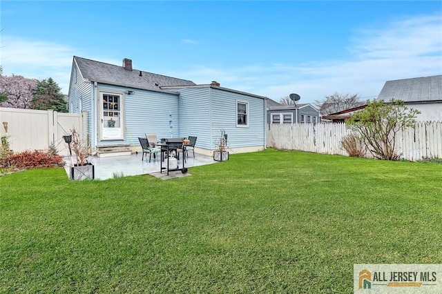 back of property featuring a fenced backyard, a chimney, a yard, and a patio