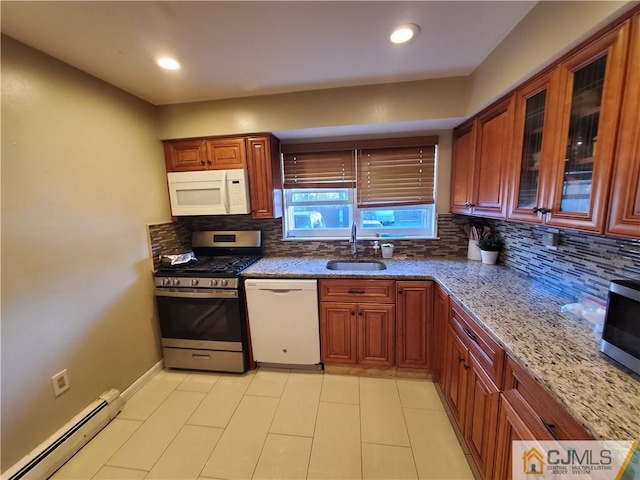 kitchen featuring a baseboard radiator, decorative backsplash, appliances with stainless steel finishes, a sink, and light stone countertops