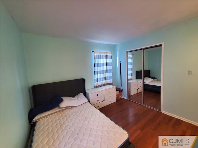 bedroom with a closet, baseboards, and dark wood-style flooring