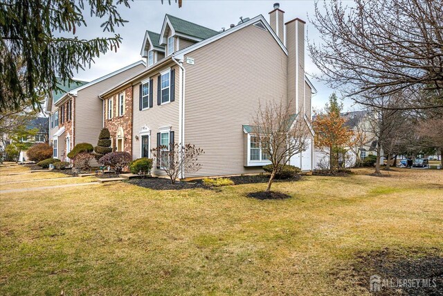 view of property exterior with a chimney and a lawn