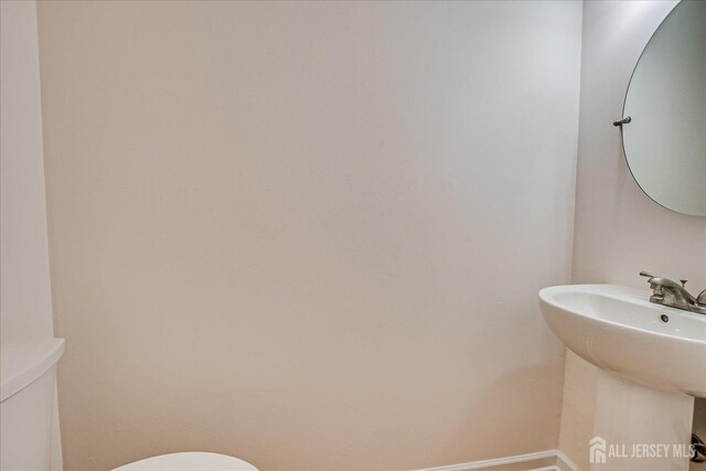 half bath featuring baseboards, a sink, and toilet