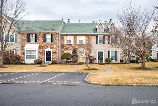 multi unit property featuring uncovered parking, a front lawn, a chimney, and brick siding