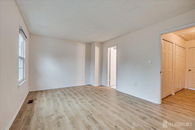 spare room with a textured ceiling, visible vents, and wood finished floors