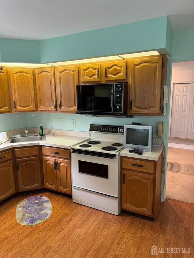 kitchen with light wood-type flooring, white range with electric stovetop, and sink