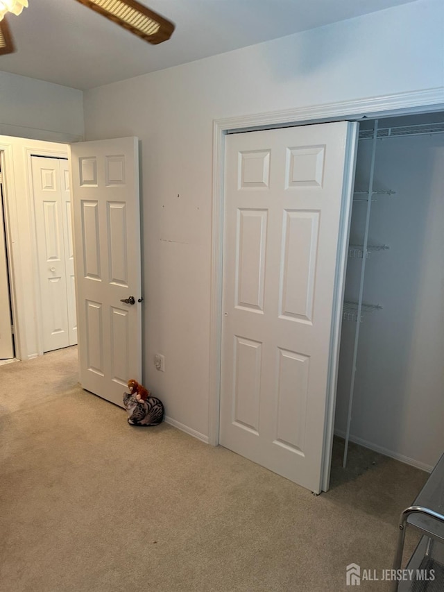 unfurnished bedroom with light carpet, a closet, and baseboards