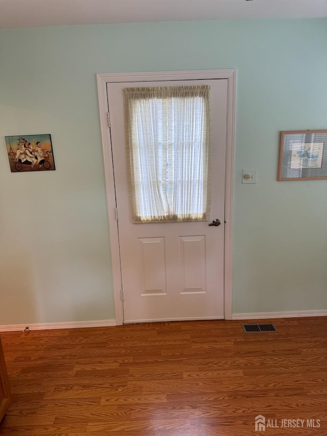 doorway to outside featuring wood finished floors, visible vents, and baseboards