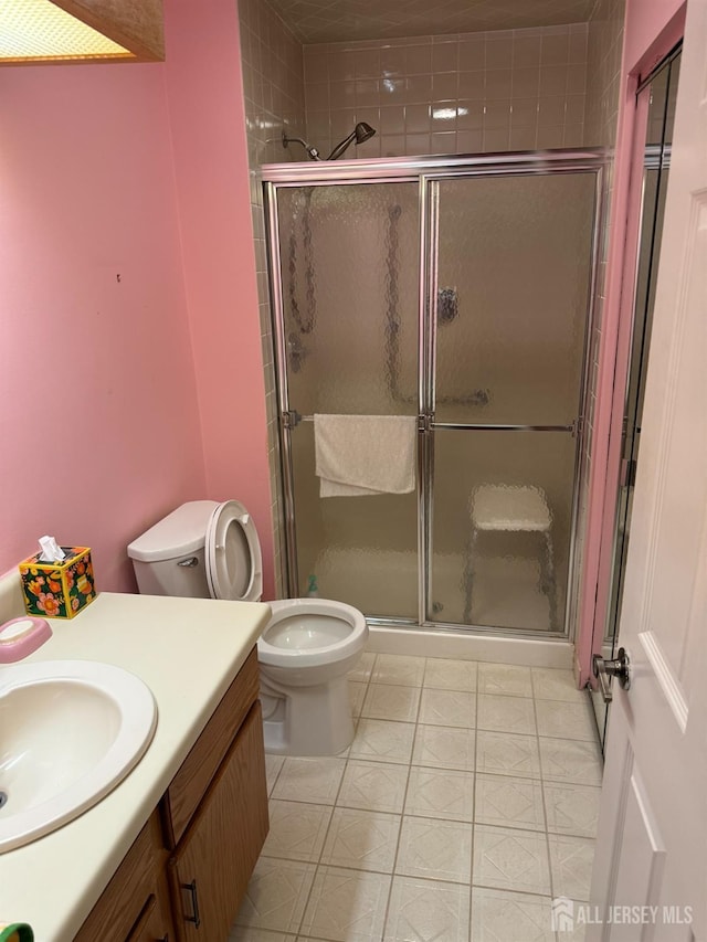 full bath with toilet, tile patterned flooring, a shower stall, and vanity