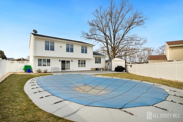 rear view of house featuring a fenced in pool, a lawn, a storage shed, a fenced backyard, and an outbuilding