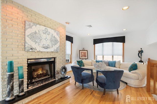 living room with visible vents, recessed lighting, a fireplace, and wood finished floors