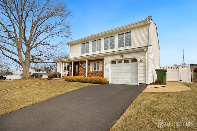 traditional-style home featuring aphalt driveway, brick siding, a front yard, and a gate