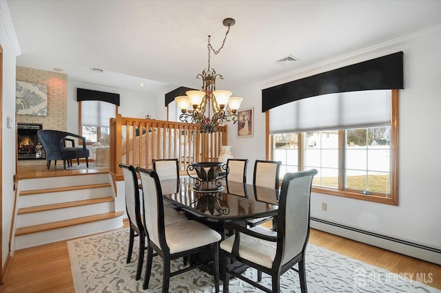 dining room featuring a baseboard heating unit, light wood-style floors, visible vents, and a wealth of natural light