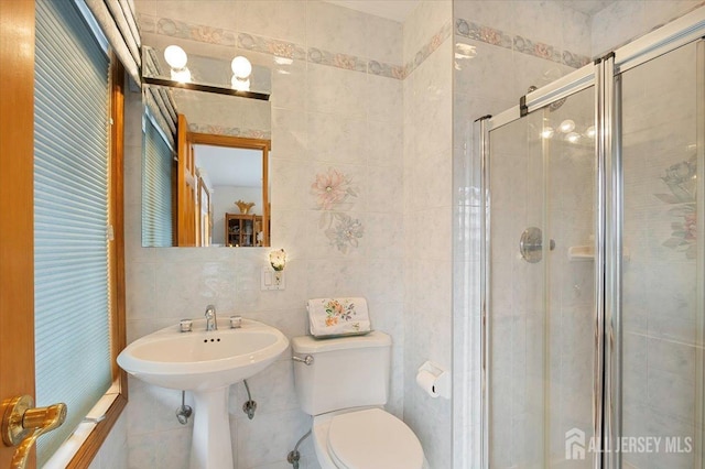 full bathroom featuring a sink, toilet, tile walls, and a shower stall