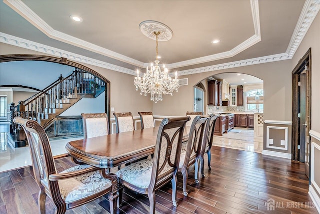 87 Ellmyer Rd, Edison, NJ 08820 - dining room with arched walkways, a chandelier, dark wood finished floors, a tray ceiling, and ornamental molding