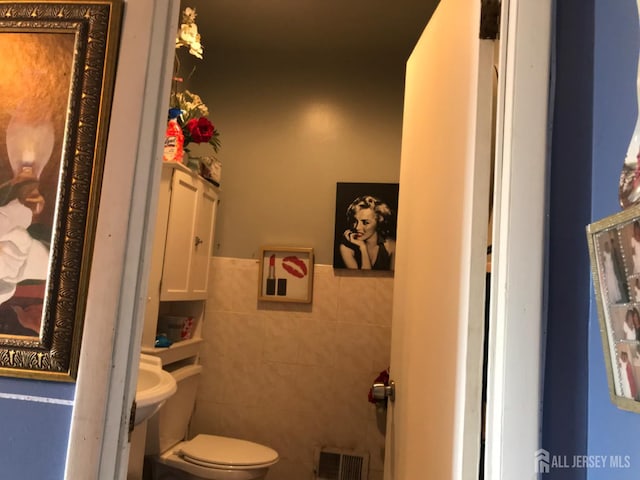 335 Alpine St, Perth Amboy, NJ 08861 - half bathroom featuring tile walls, toilet, and a wainscoted wall