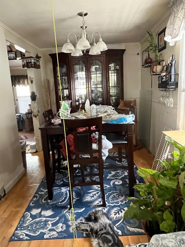 dining space with ornamental molding, wood-type flooring, and a notable chandelier