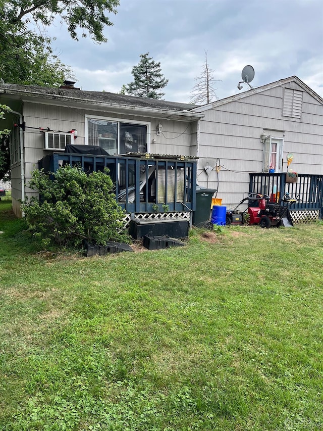 back of property with a wooden deck and a yard